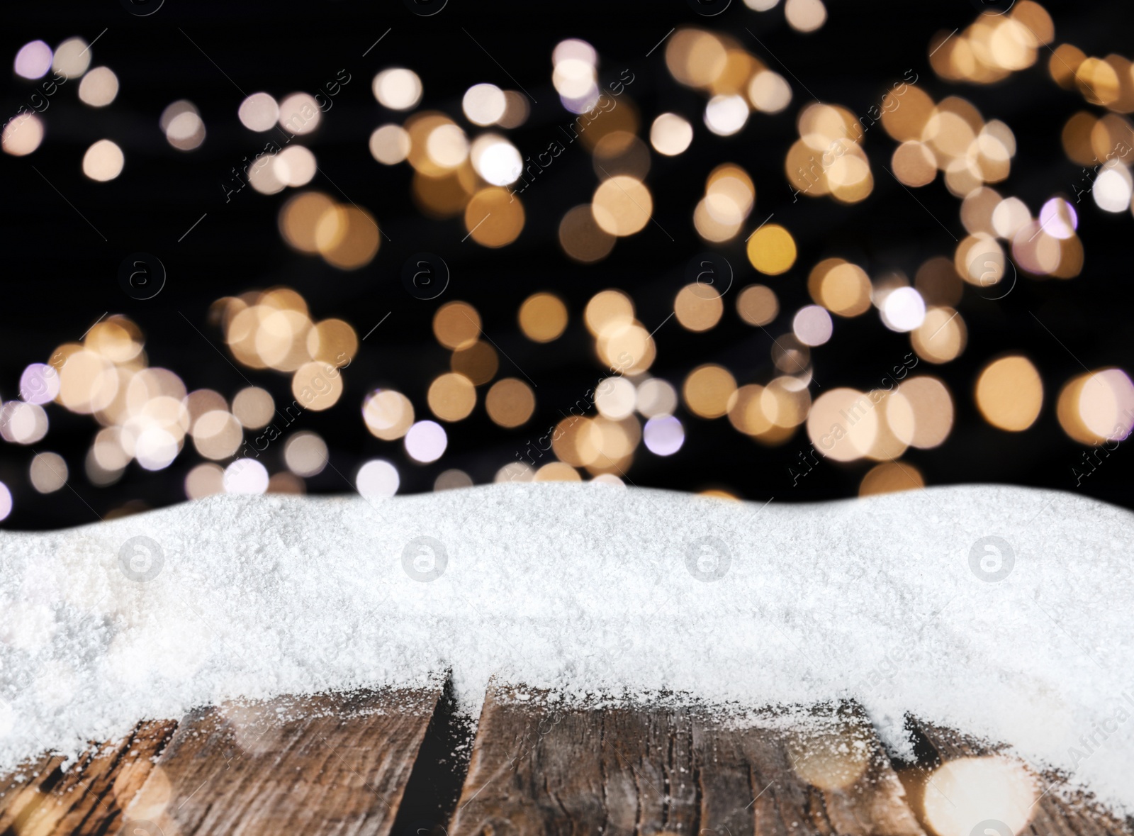 Image of Wooden surface with heap of snow and blurred Christmas lights on background, bokeh effect 