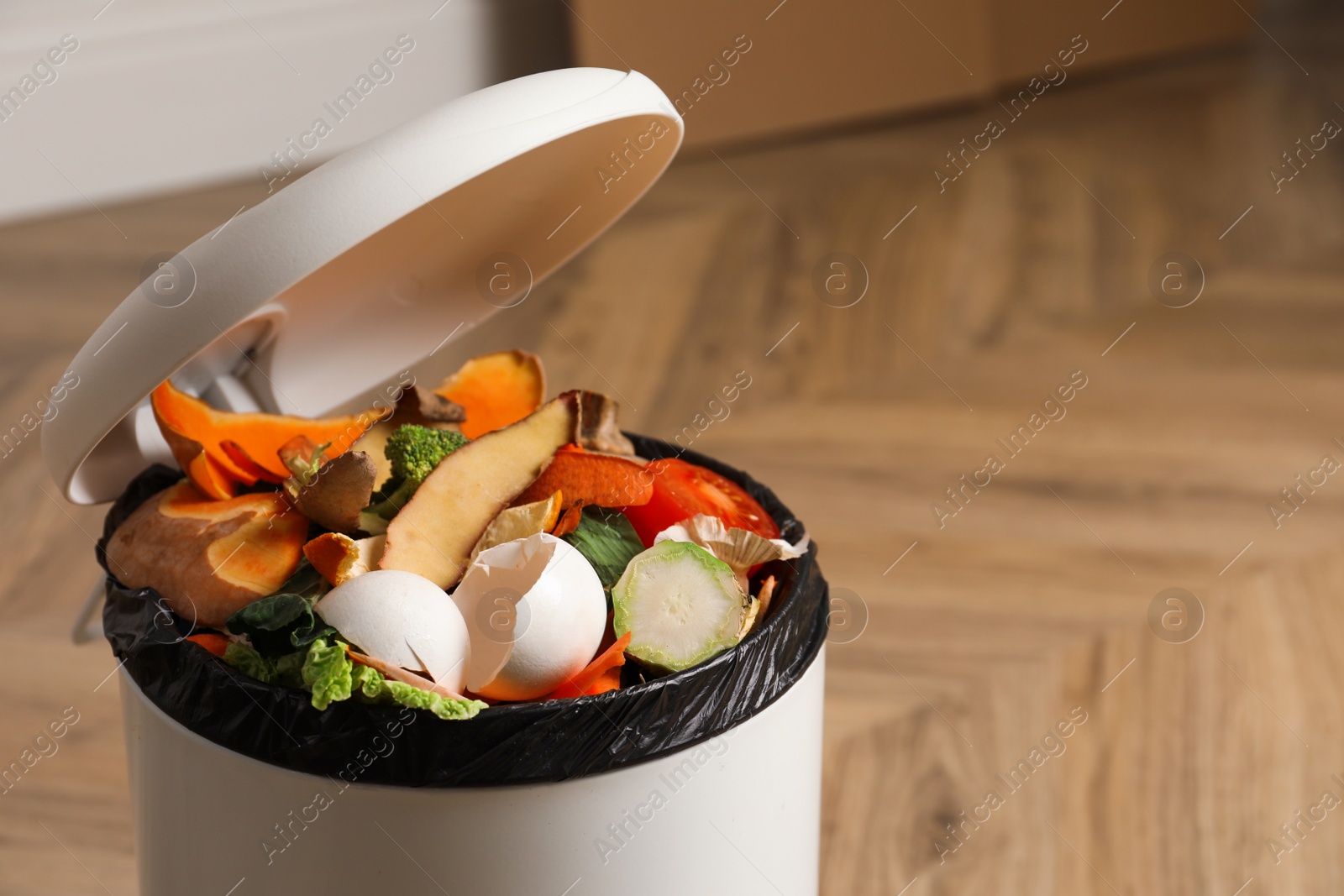 Photo of Natural garbage in trash bin indoors, closeup with space for text. Composting of organic waste