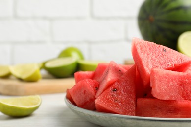 Photo of Slicesdelicious watermelon and limes on white wooden table, closeup. Space for text