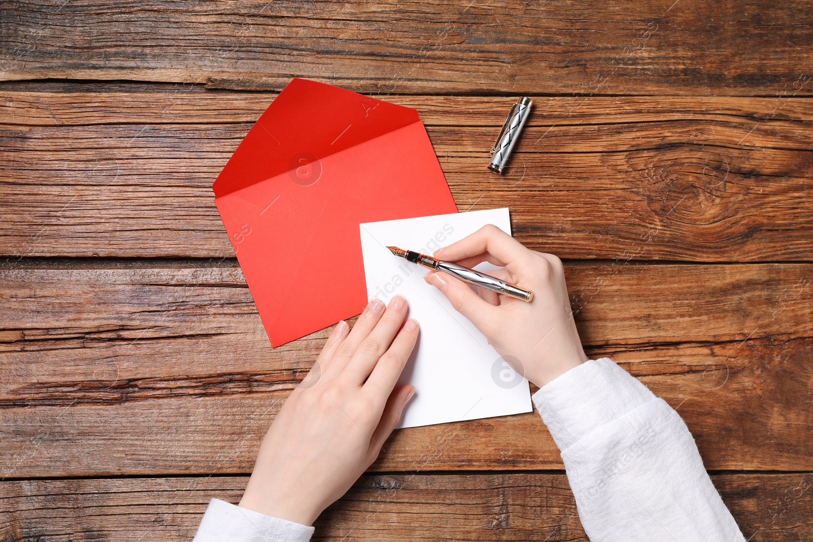 Photo of Woman writing letter at wooden table, top view