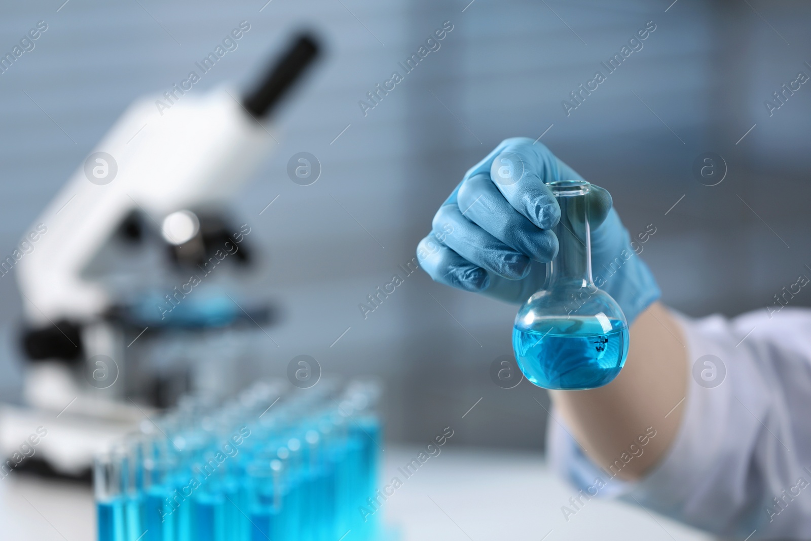 Photo of Scientist holding flask in laboratory, space for text