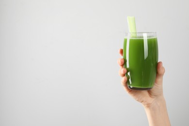 Woman holding glass of delicious celery juice on light grey background, closeup. Space for text