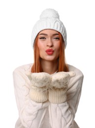 Photo of Young woman in hat and mittens blowing kiss on white background. Christmas celebration
