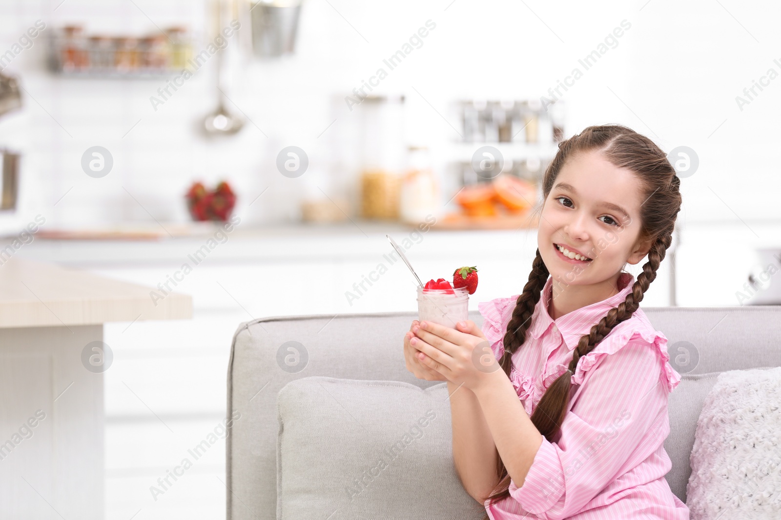 Photo of Cute girl eating tasty yogurt at home