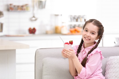 Cute girl eating tasty yogurt at home