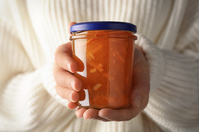 Photo of Woman with jar of orange jam, closeup