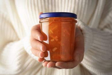 Woman with jar of orange jam, closeup