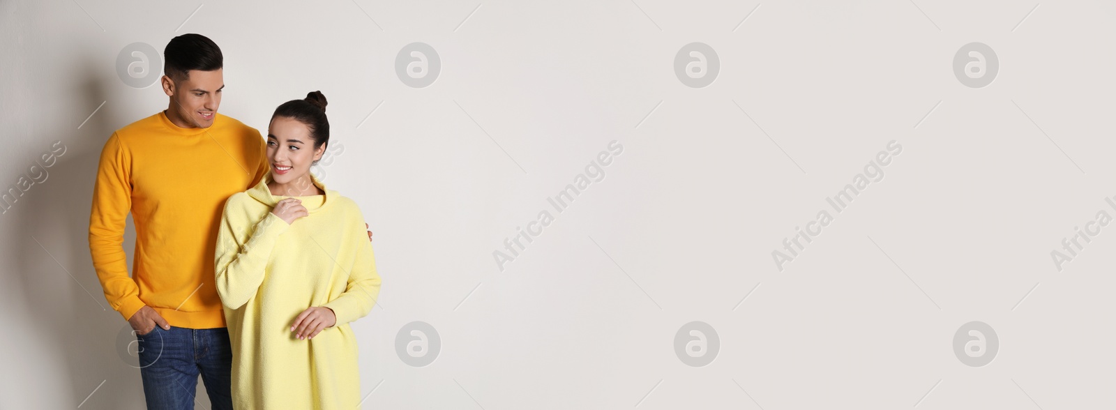 Photo of Happy couple wearing yellow warm sweaters on white background. Space for text