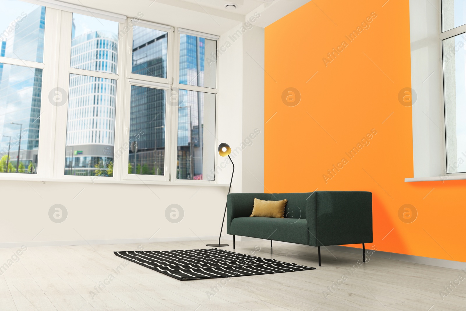 Photo of Beautiful interior with sofa and floor lamp near orange wall