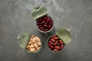 Tin cans with different canned kidney beans on grey table, flat lay