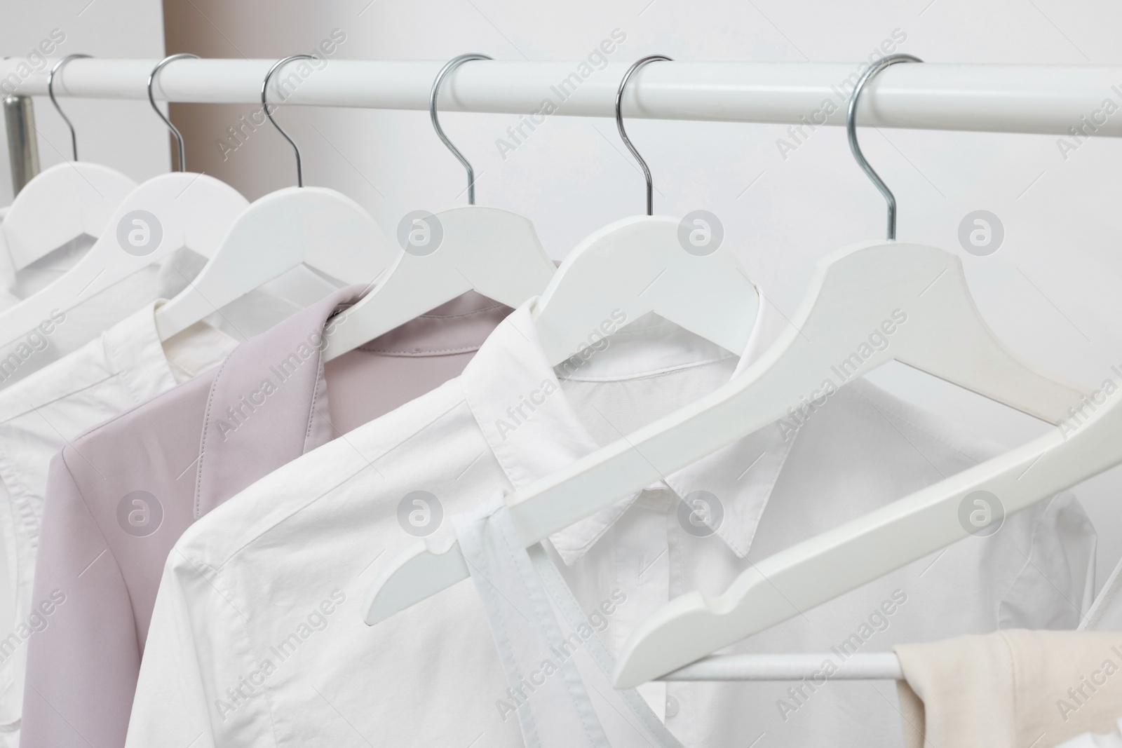 Photo of Rack with different stylish women`s clothes near white wall