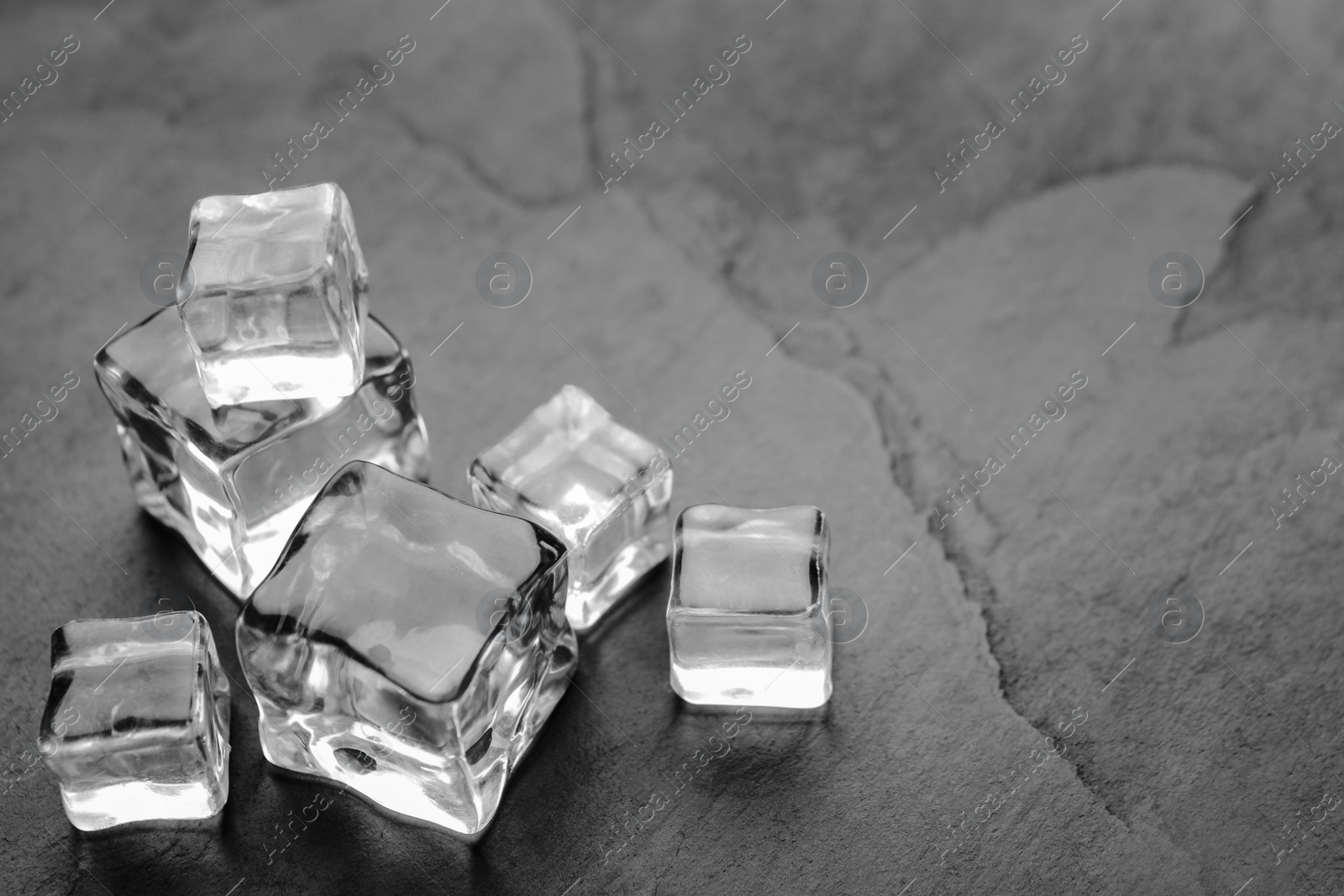 Photo of Crystal clear ice cubes on grey table, closeup. Space for text