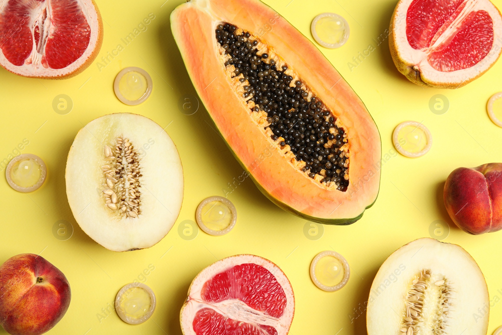 Photo of Flat lay composition with condoms and exotic fruits on yellow background. Erotic concept