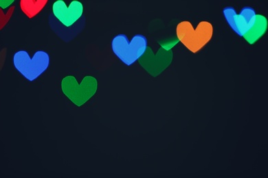 Photo of Blurred view of beautiful heart shaped lights on dark background. Space for text