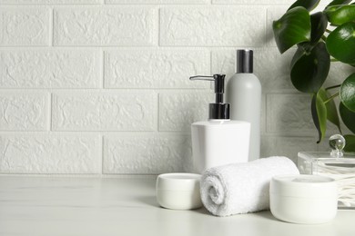 Different bath accessories and personal care products on white table near brick wall, space for text