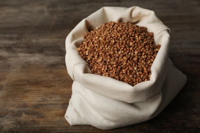 Uncooked buckwheat in sackcloth bag on wooden table