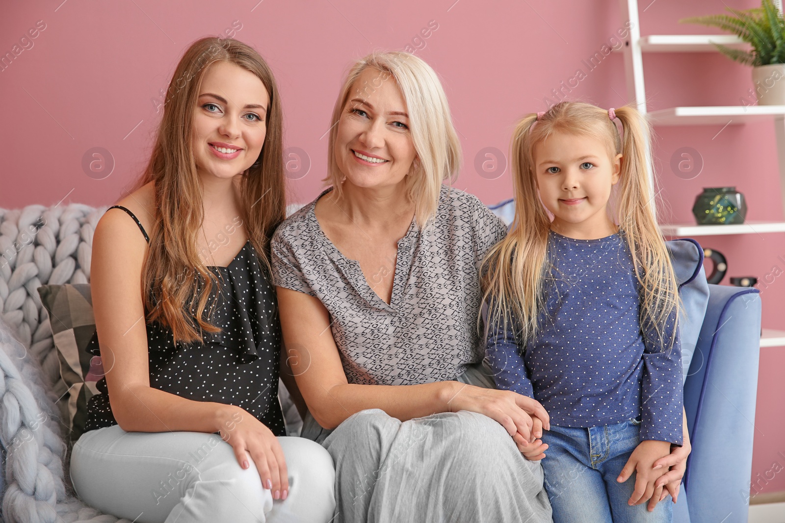 Photo of Happy young woman with her mother and daughter at home