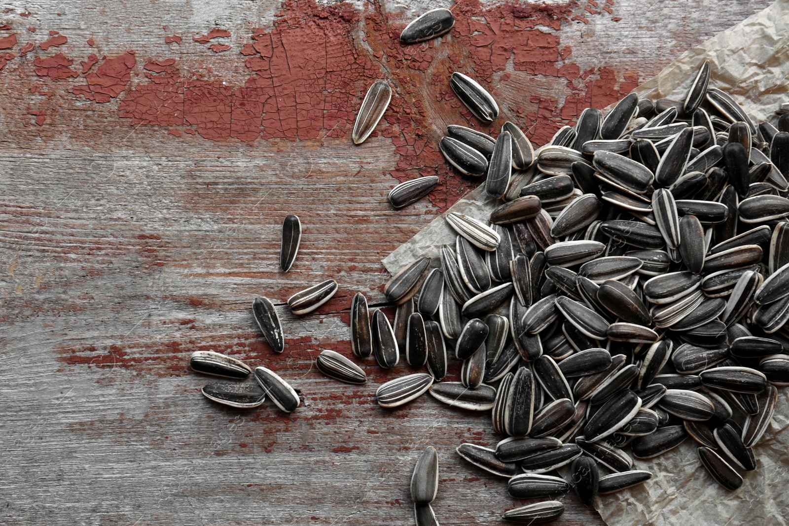 Photo of Pile of sunflower seeds on wooden table, flat lay. Space for text