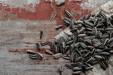 Photo of Pile of sunflower seeds on wooden table, flat lay. Space for text
