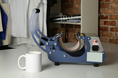 Photo of Printing logo. Heat press and cup on white table, space for text