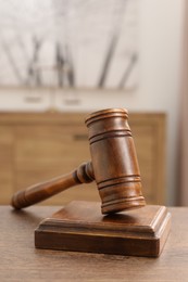 Photo of Wooden gavel and sound block on table indoors, closeup. Space for text