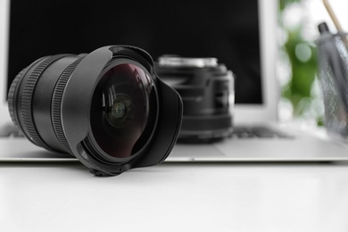 Photo of Camera lenses and laptop on white table. Equipment for professional photographer