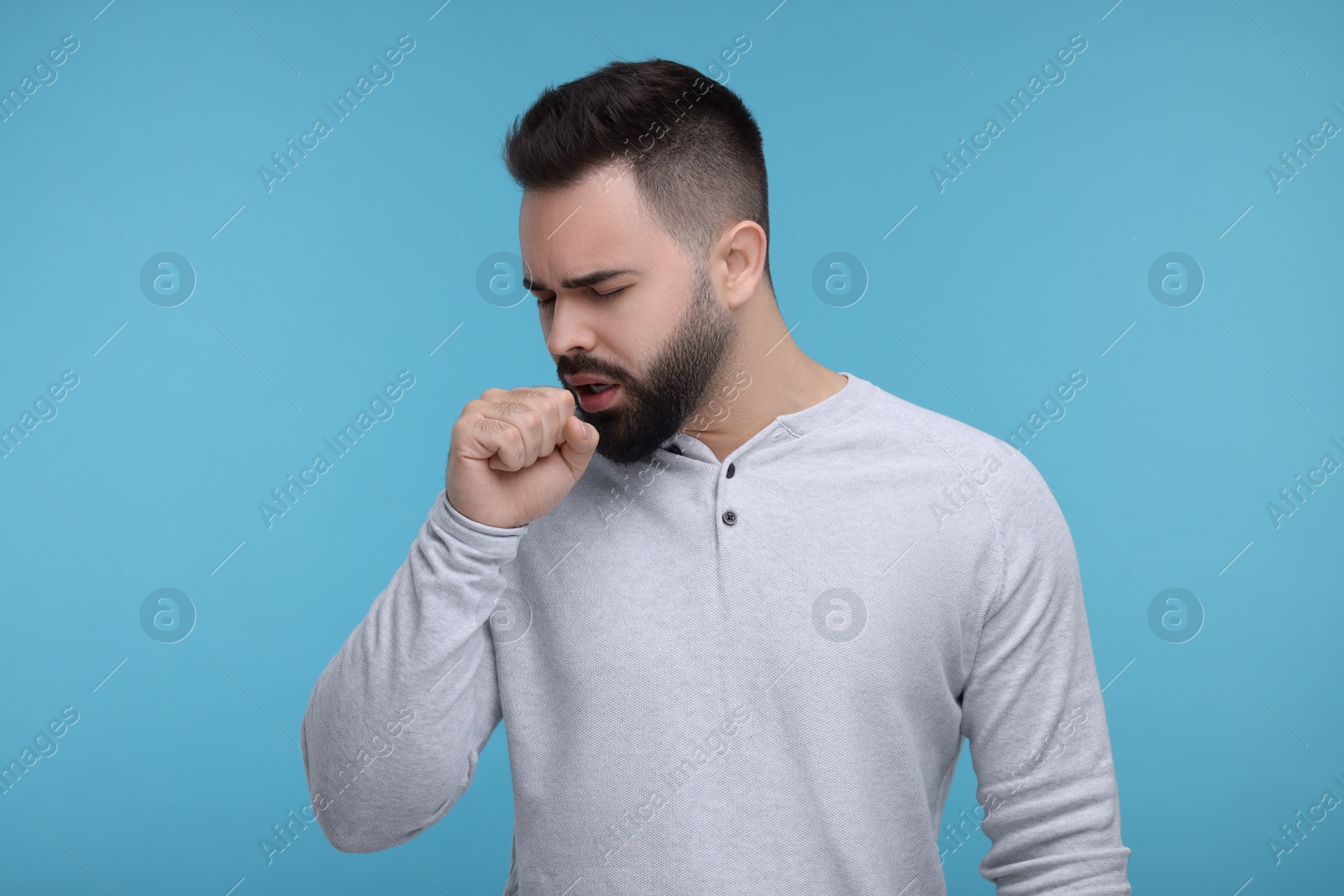 Photo of Sick man coughing on light blue background