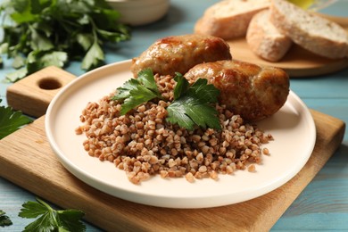 Photo of Tasty buckwheat with fresh parsley and cutlets on light blue wooden table, closeup