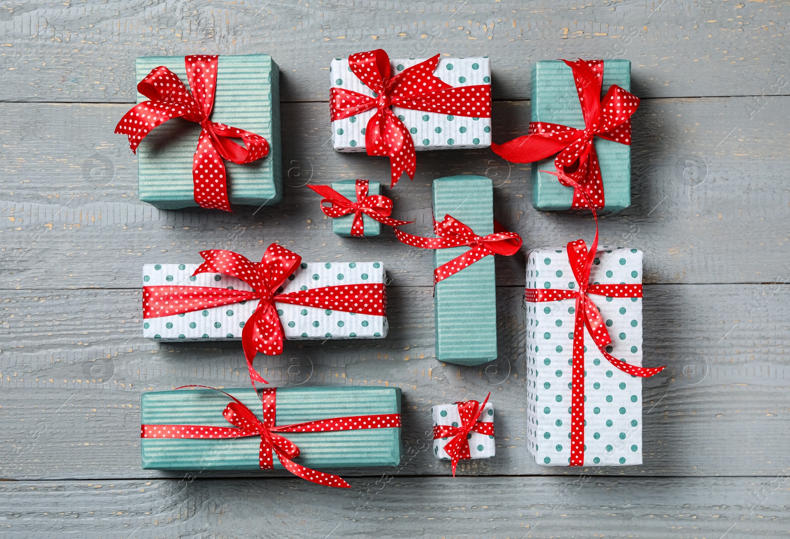 Photo of Christmas gift boxes with red bows on grey wooden background, flat lay