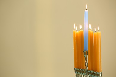 Hanukkah celebration. Menorah with burning candles on beige background, space for text