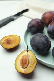 Photo of Tasty ripe plums on white table, closeup