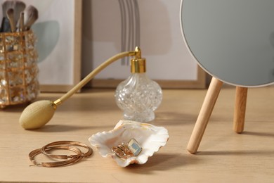 Mirror, jewelry and perfume on wooden dressing table