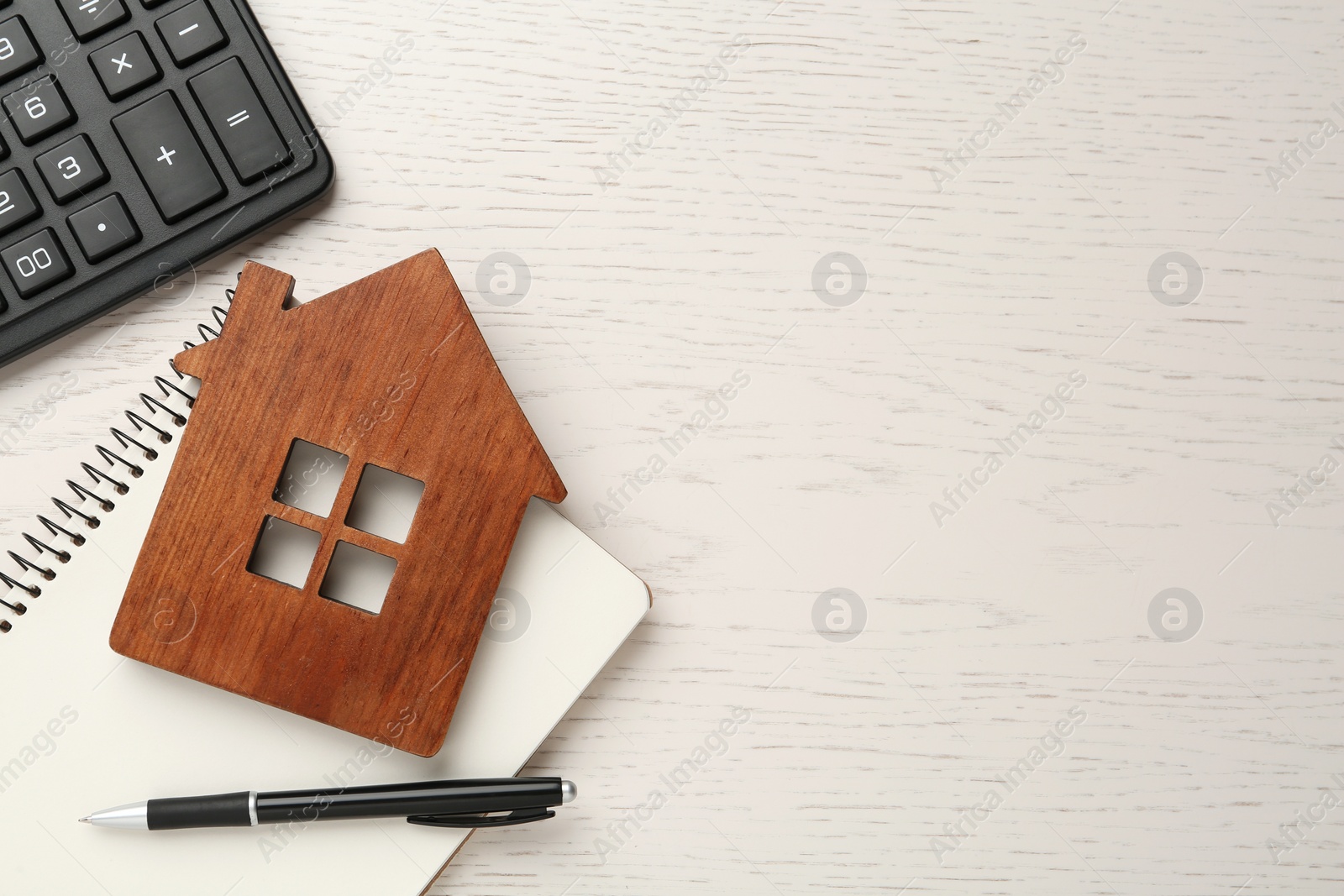 Photo of Mortgage concept. House model, notebook, pen and calculator on white wooden table, flat lay with space for text