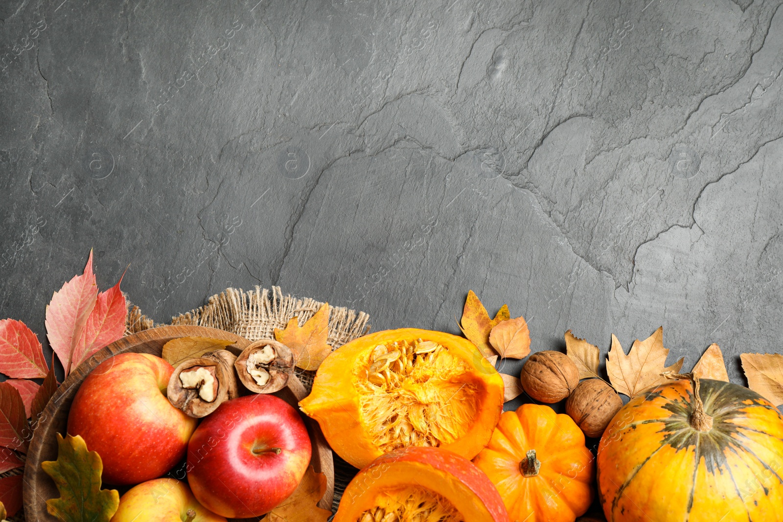 Photo of Flat lay composition with vegetables, fruits and autumn leaves on black slate table, space for text. Thanksgiving Day