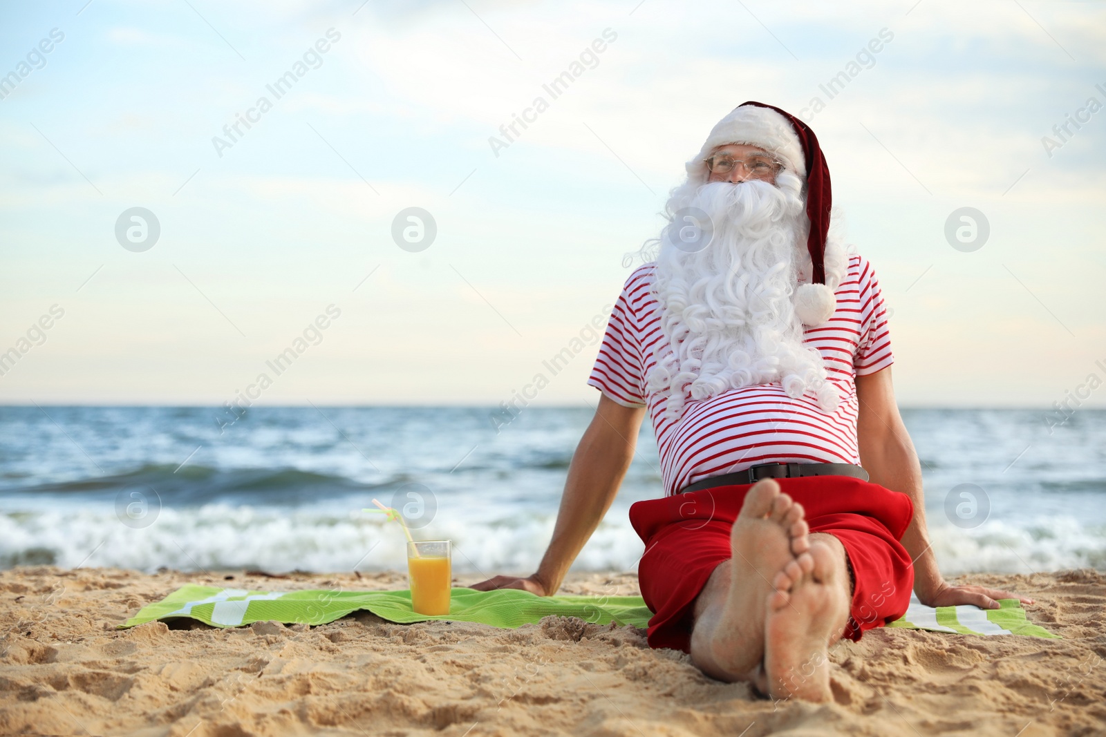 Photo of Santa Claus with cocktail relaxing on beach, space for text. Christmas vacation