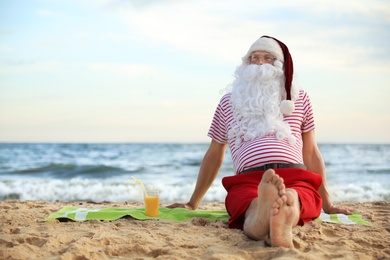 Santa Claus with cocktail relaxing on beach, space for text. Christmas vacation
