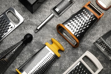 Photo of Different modern graters on grey table, flat lay