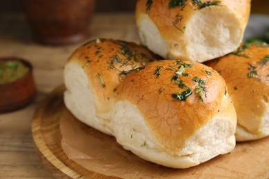 Traditional pampushka buns with garlic and herbs on wooden board, closeup