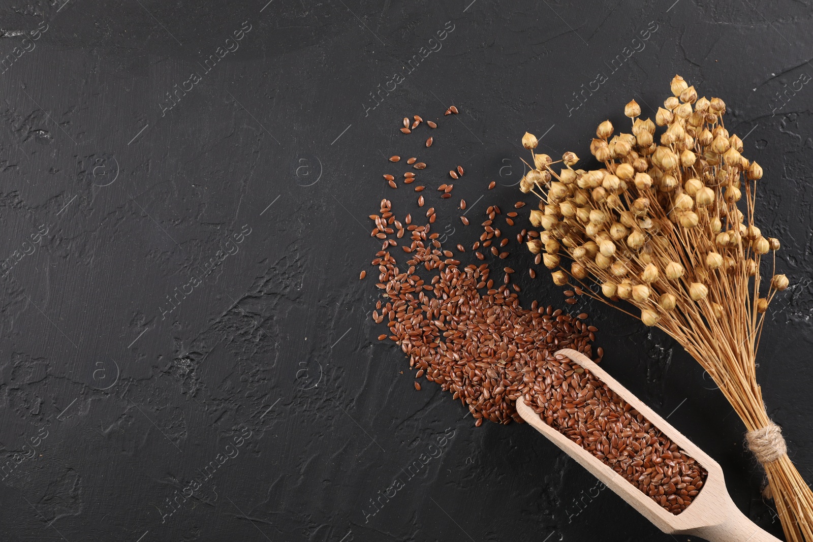 Photo of Flax seeds and dry flowers on grey textured table, flat lay. Space for text