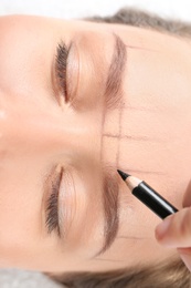 Photo of Young woman having eyebrow correction procedure in beauty salon, closeup