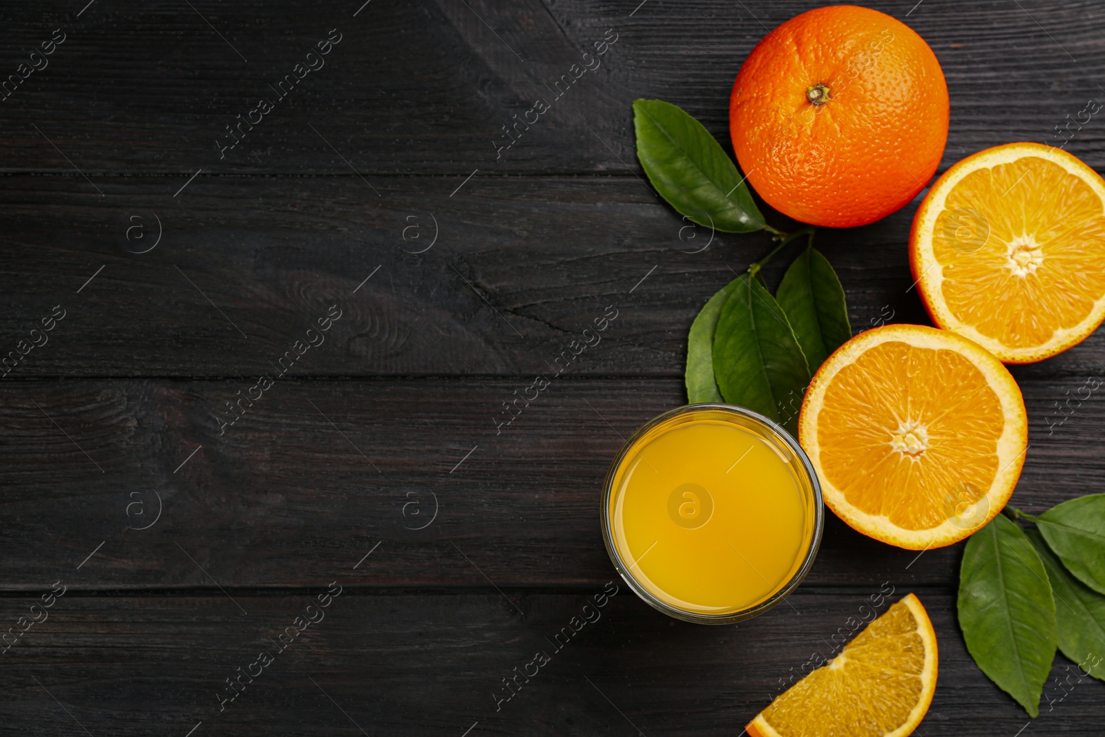 Photo of Delicious orange juice and fresh fruits on black wooden table, flat lay. Space for text