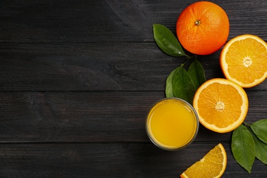 Delicious orange juice and fresh fruits on black wooden table, flat lay. Space for text