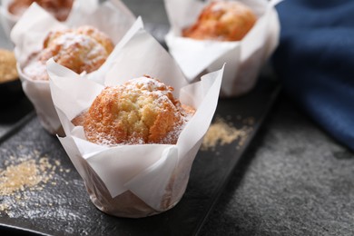 Photo of Delicious muffins with powdered sugar on grey table, closeup