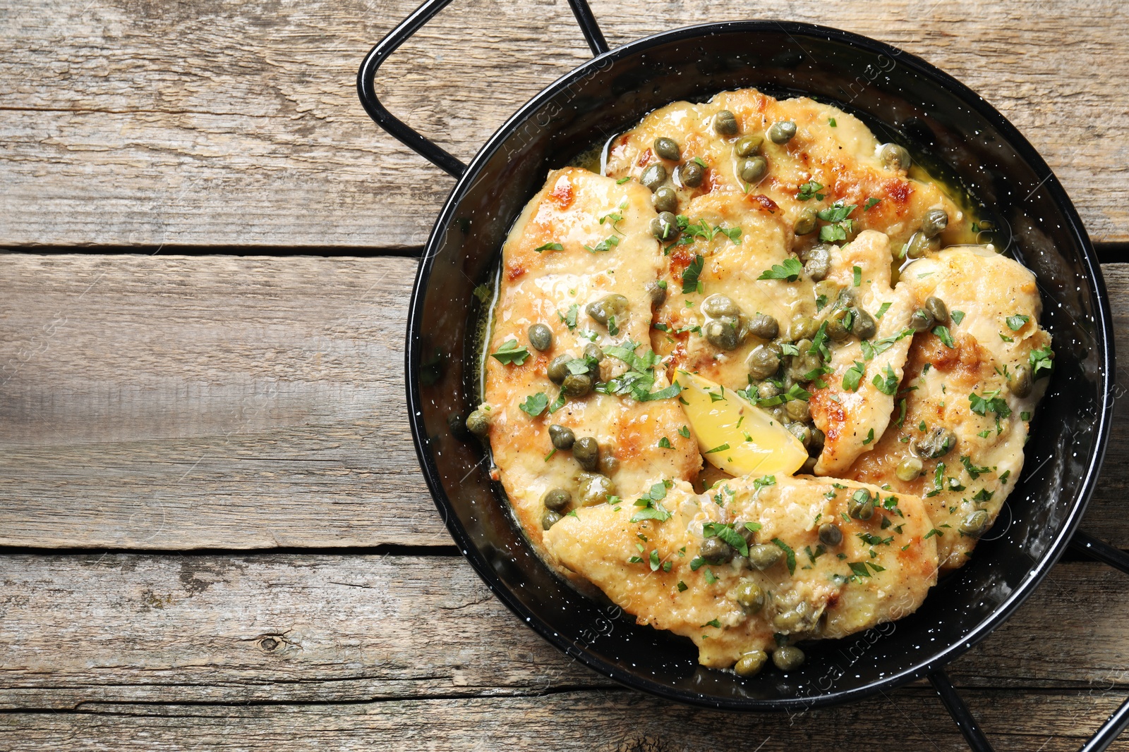 Photo of Delicious chicken piccata with herbs on wooden table, top view. Space for text