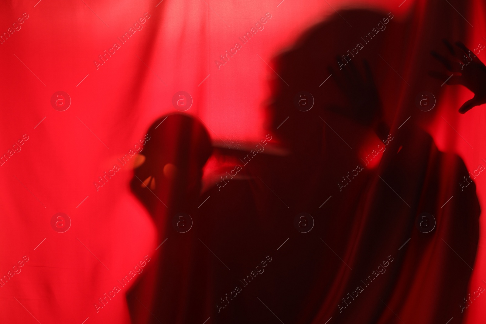 Photo of Silhouette of creepy ghost with skull behind red cloth