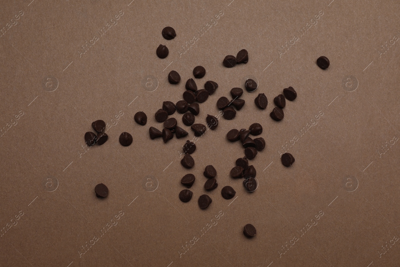 Photo of Pile of delicious chocolate chips on brown background, top view