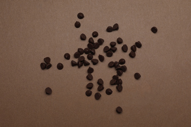 Pile of delicious chocolate chips on brown background, top view