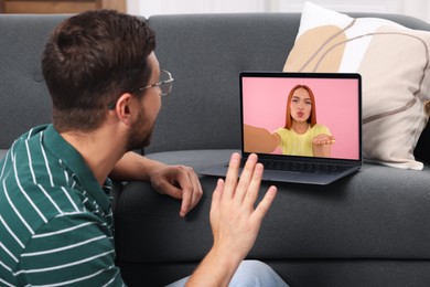 Image of Long distance love. Man having video chat with his girlfriend via laptop at home