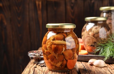 Photo of Delicious marinated mushrooms in glass jar on wooden table