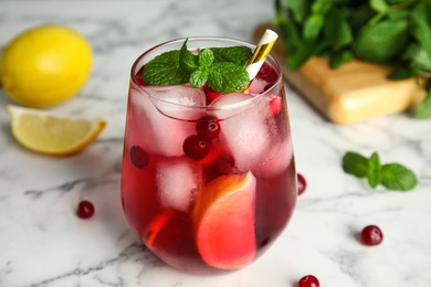 Photo of Tasty refreshing cranberry cocktail with mint on white marble table